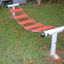 Red and white Bridge playground equipment on grass.