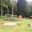 Sandbox with bark in a playground surrounded by trees and benches.