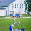 Yacht Swing rocking in playground area with green grass and white building in background