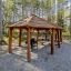 Wooden shelter Long Firehouse with picnic tables and grill in a forest.