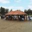 Wooden gazebo named Long Firehouse in a park, surrounded by people