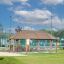 Long Firehouse wooden playground shelter with benches and picnic tables outdoors.