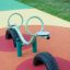 SeeSaw playground equipment with tire base on colorful rubber surface.