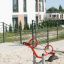 Modern red SeeSaw playground equipment in a sandy play area.