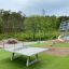 Playground equipment including Triple Somersault and a ping pong table on artificial grass.