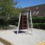 Medusa steel structure in a playground setting with climbing wall and ladder.