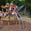 Children playing on Sherwood wooden playhouse at a park.