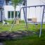 Silver Double Swing in a playground surrounded by green grass and play equipment.