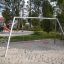 Silver Double Swing in a playground with sand and nearby park equipment.