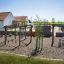 Yellowstone wooden playhouse in a playground with various wooden structures and a child playing near