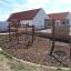 Yellowstone wooden playhouse in a playground with swings and climbing structures