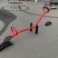 Red seesaw on playground with tire ends and handles.