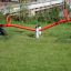 Red Seesaw on a grassy playground with black tire support.