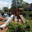 Yosemite playground set with a slide and climbing wall in residential area.