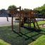 Serengeti wooden playhouse on playground with climbing nets and slide.