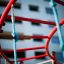 Playground equipment featuring Dolphin steel structure with red bars and blue ropes for climbing.