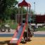 Ladybird playhouse with slide in a playground setting'