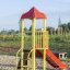 Ladybird playhouse with slide in an outdoor playground.