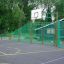 Outdoor sports court with basketball hoop and green fencing. San Siro.