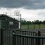 Basketball court with green metal fencing and a cloudy sky.