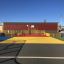 Multi-colored sports court Maracana with basketball hoop, surrounded by yellow fences.