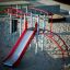 Playground structure with red and silver slide and climbing elements.