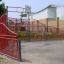 Red Olimpico playground basketball court with metal fencing.