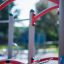 Butterfly steel structure playground equipment with red curved bars and ropes.