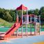 Red playground equipment with slide and climbing areas, Spider steel structure.