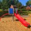 Red and blue Crow's Nest steel structure play set with slide on playground.