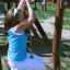 Girl playing on the Kampinos wooden playhouse climbing rope.