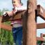 Girl playing on the Kampinos wooden playhouse outdoors.