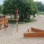 Nature Ship Sandbox, wooden playhouse in a sandy playground with surrounding trees.