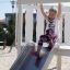 Girl sliding down Nature Ship Sandbox, wooden playhouse slide