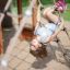 Child playing on the rope net of the Nature Ship Sandbox, wooden playhouse.