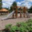 Playground equipment set Alstad with slide, climbing wall, and wooden structures.