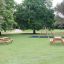 Larchwood Table & Bench in a park setting with trees and a playground.
