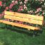 Wooden bench with steel construction in a garden with blooming flowers.