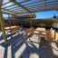 Wooden outdoor Table & Bench sets under a wooden pergola in a paved area.