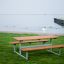 Outdoor Table & Bench set near a waterfront with grass area.