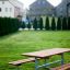 Table & Bench set in a green park area with houses in the background.