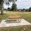 Table & Bench in a park with playground in the background.