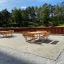 Tables & benches arrangement of Table & Bench Quadro in an outdoor setting with green trees in the b