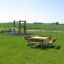 Table & Bench Quadro in a green park area with a playground in the background.