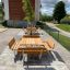 Outdoor wooden Table & Bench Quadro set on a paved area with greenery in the background