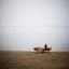 Outdoor Table & Bench Quadro setup on a sandy beach with a lake in the background.