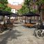 Public outdoor seating with Table & Bench Quadro sets under umbrellas.