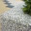 Close-up of Berta concrete bench with exposed aggregate finish and greenery in the background.