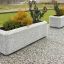 Concrete planters Milano with plants on a paved surface.