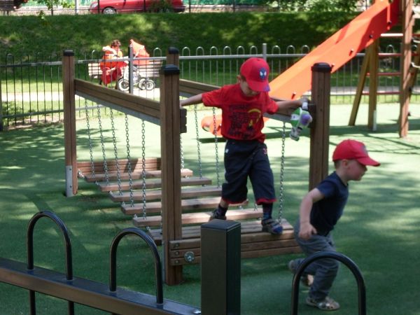 Children playing on a playground bridge with artificial grass surface